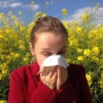 woman sneezing into tissue suffering from seasonal allergies due to poor gut health