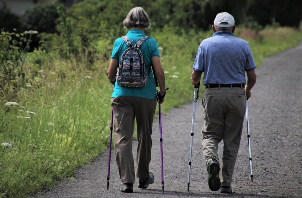 Two seniors exercising on a hike down a road shows how exercise is beneficial to seniors